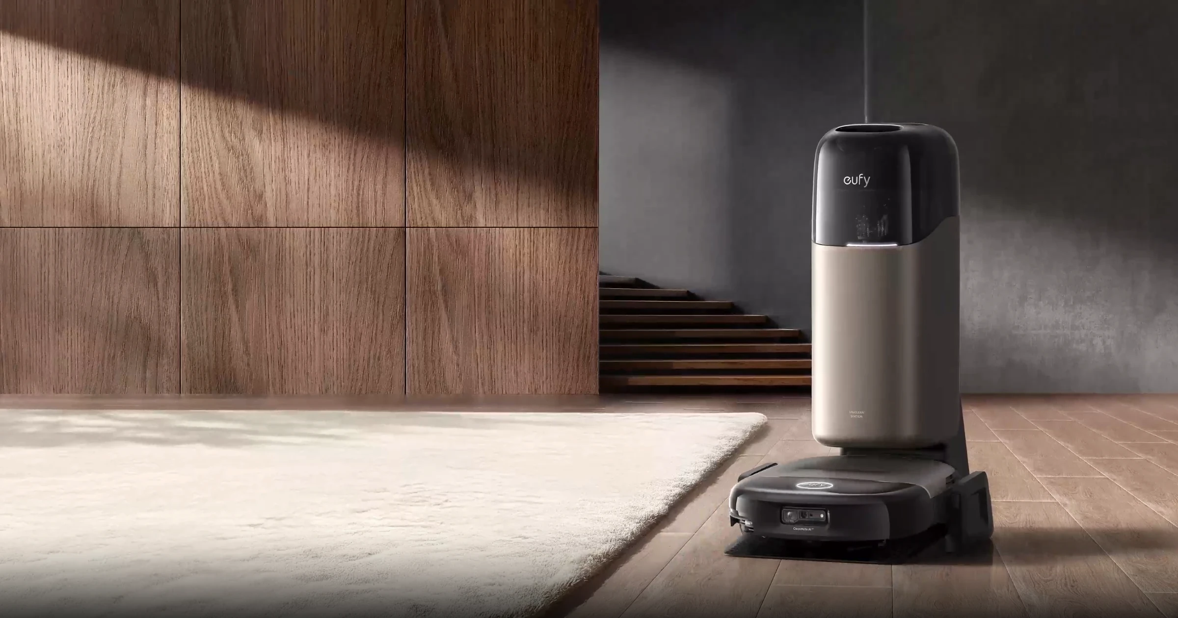 Frame from Eufy promotional video showing the Omni S2 and base station on a hard wood floor covered with a rug. A staricase shown in the background.